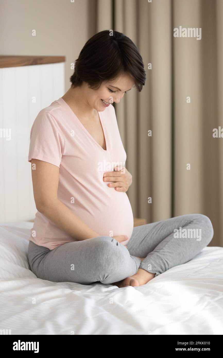 Sorridente donna incinta toccare carezza baby bump Foto Stock
