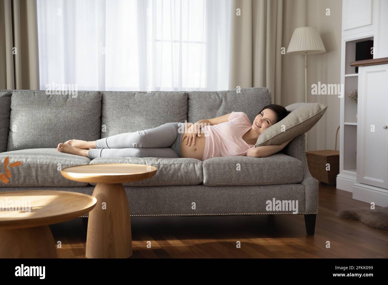 Donna in gravidanza felice rilassarsi a casa toccando bump Foto Stock