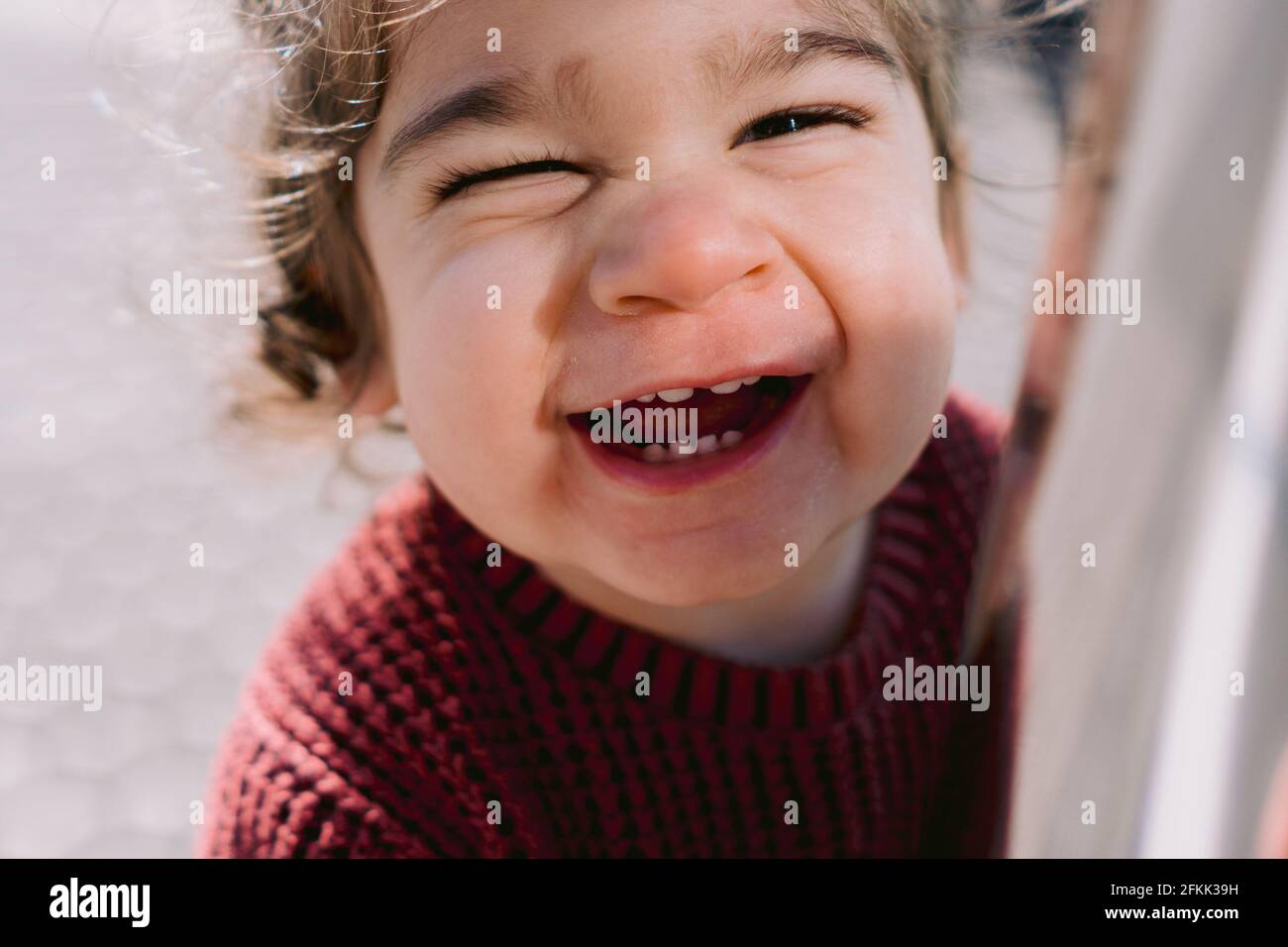 Primo piano di divertente adorabile Toddler Laughing e guardando fotocamera con nuovi denti e giacca viola. Concetto di felicità. Foto Stock