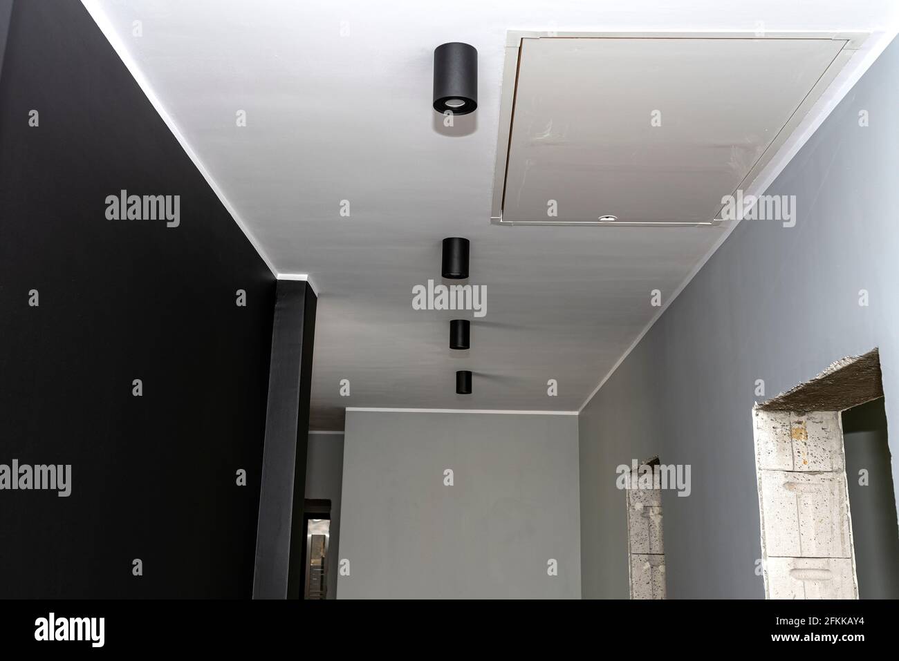 Moderna illuminazione a LED a forma di tubo, rivestita di vernice nera opaca, sospesa al soffitto. Foto Stock