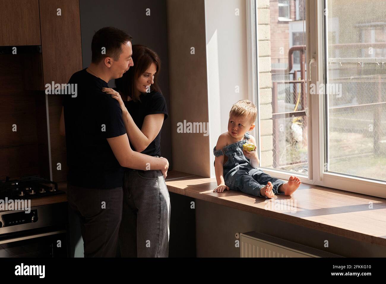 mamma e papà si abbracciano e guardano il loro bambino Foto Stock