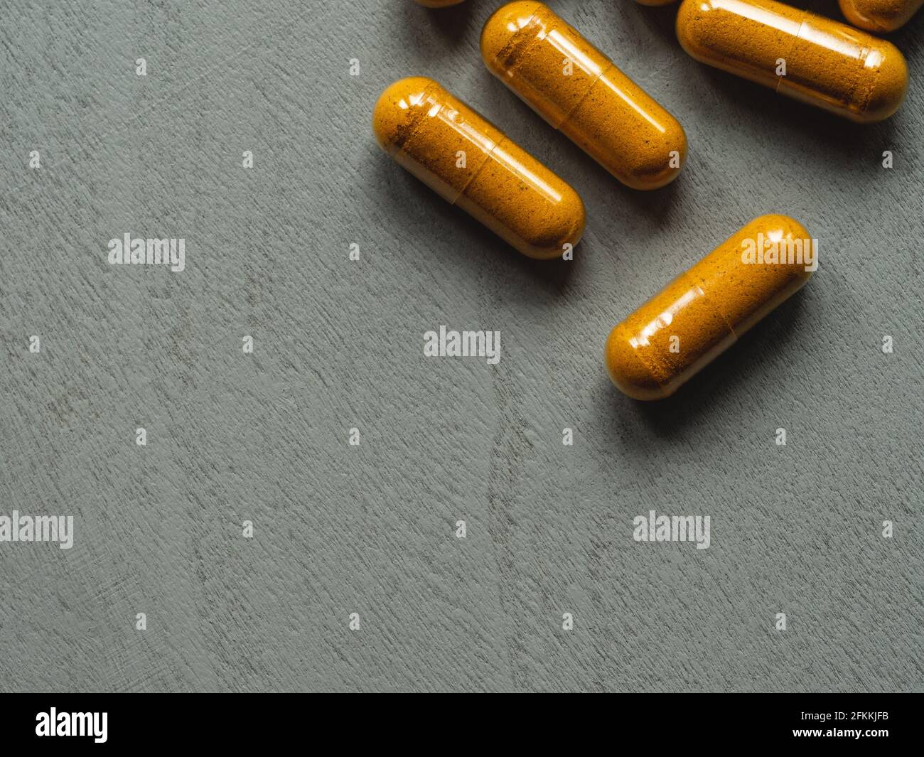 capsule turmeriche gialle su sfondo grigio di legno Foto Stock