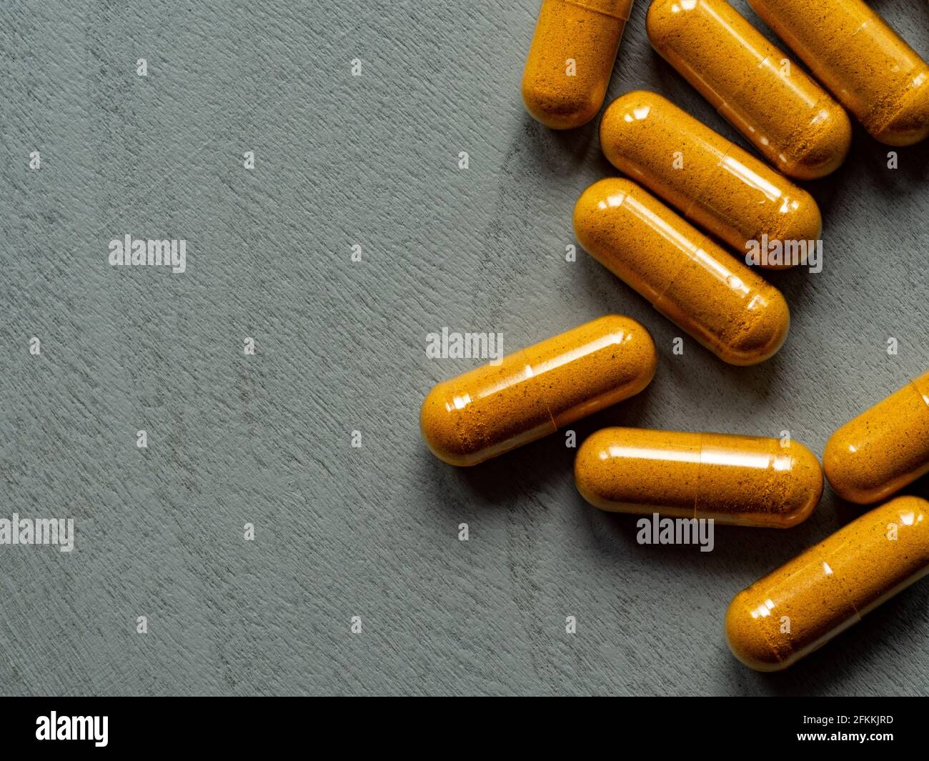 capsule curcuma su fondo grigio di legno con spazio per la copia Foto Stock