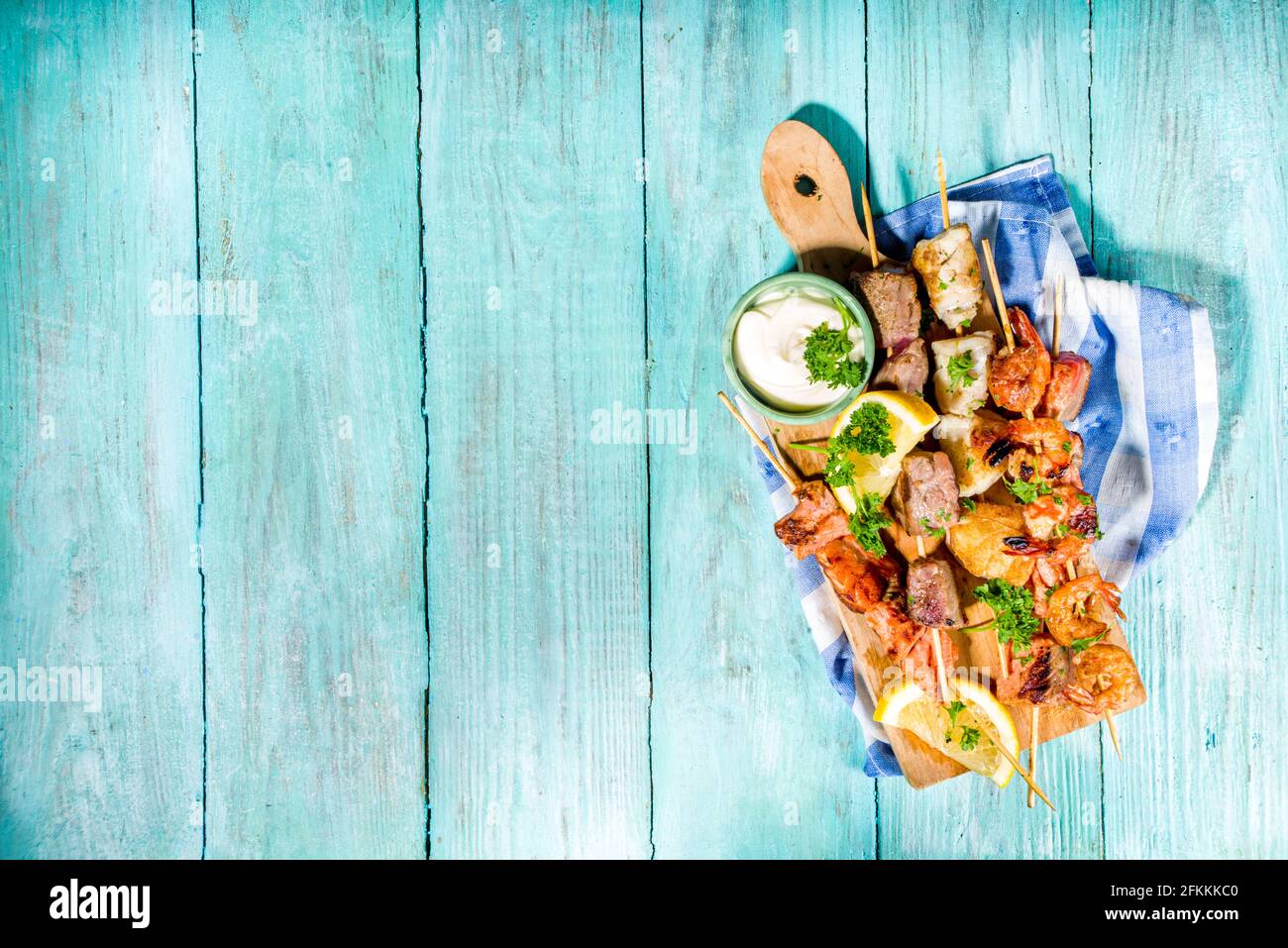 Assortimento barbecue vari piatti mediterranei alla griglia - pesce, gamberi, granchio, cozze, kebab con salse, azzurro sunne sfondo di legno Foto Stock