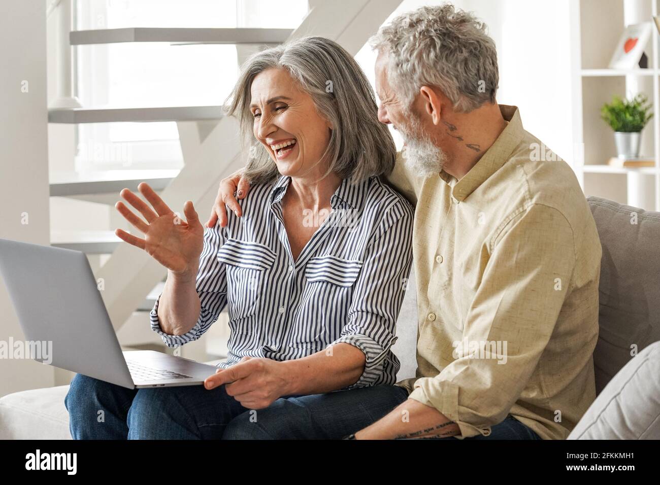 Felice vecchia coppia matura che vacilla avendo riunione virtuale sul laptop a casa. Foto Stock