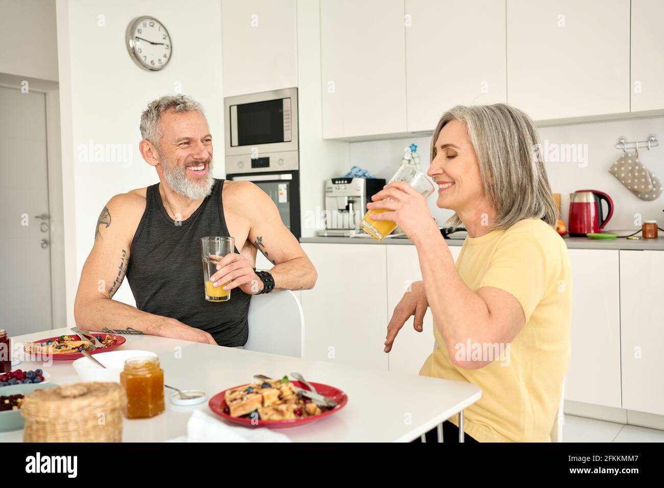 Felice sano fit coppia di famiglia anziana facendo colazione sedersi al tavolo da cucina. Foto Stock
