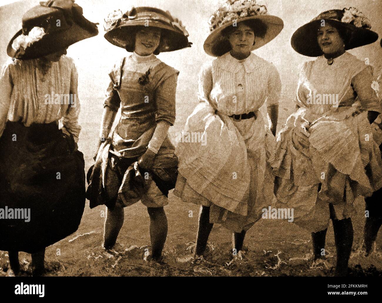 1908 - un gruppo di 'Beach Belles' inglesi, donne completamente vestite in cappelli e petticoat, prendendo una pagaia in mare a Brighton. Foto Stock