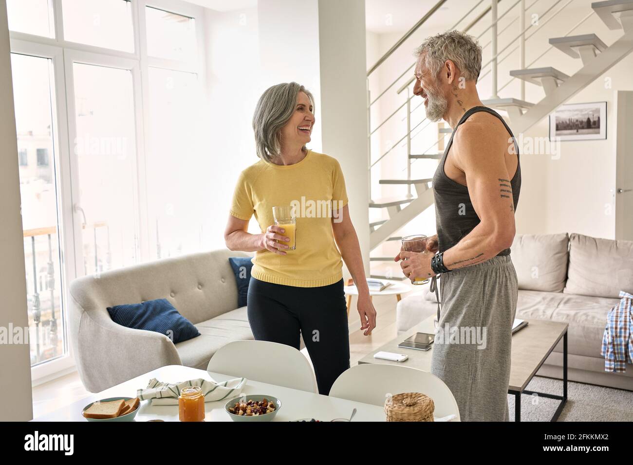 Felice sano fit matura famiglia coppia bere succo e ridere a casa. Foto Stock