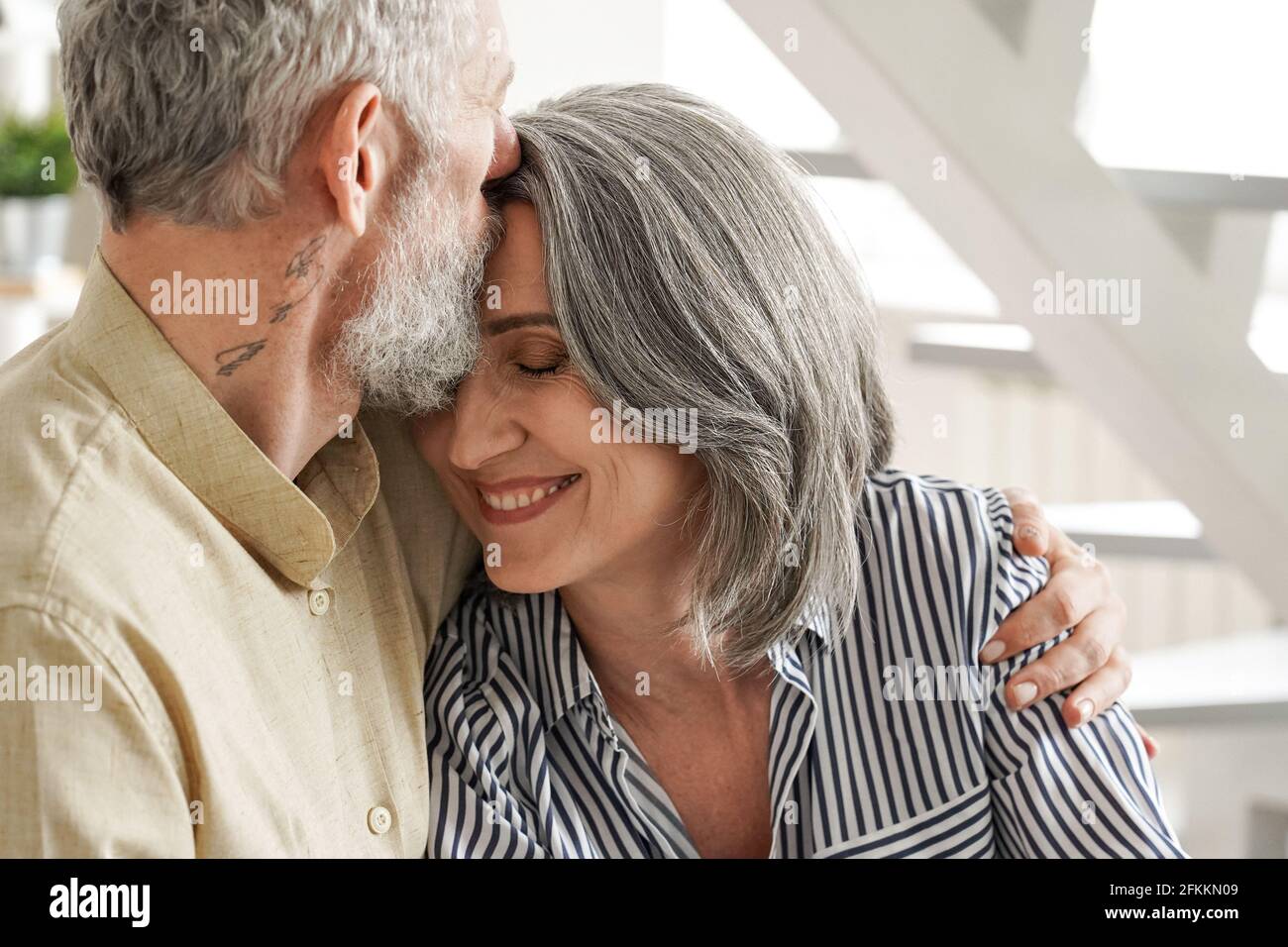 Felice affettuoso marito maturo abbracciando moglie baciante godendo di tenerezza. Foto Stock