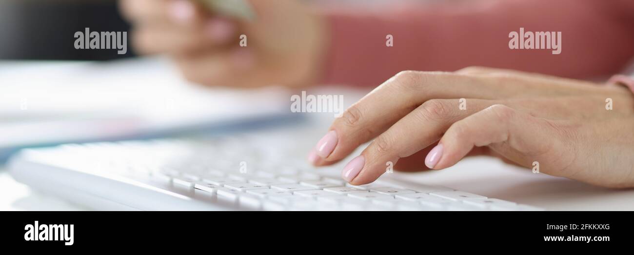 Mano femminile sulla tastiera in seconda mano tenendo credito carta bancaria Foto Stock