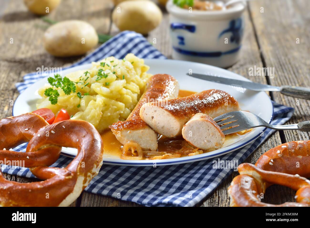 Salsicce bavaresi fritte, il cosiddetto Wollwurst, una specialità simile alla salsiccia di vitello tedesca ma senza rivestimento, servita con insalata di patate fatta in casa Foto Stock