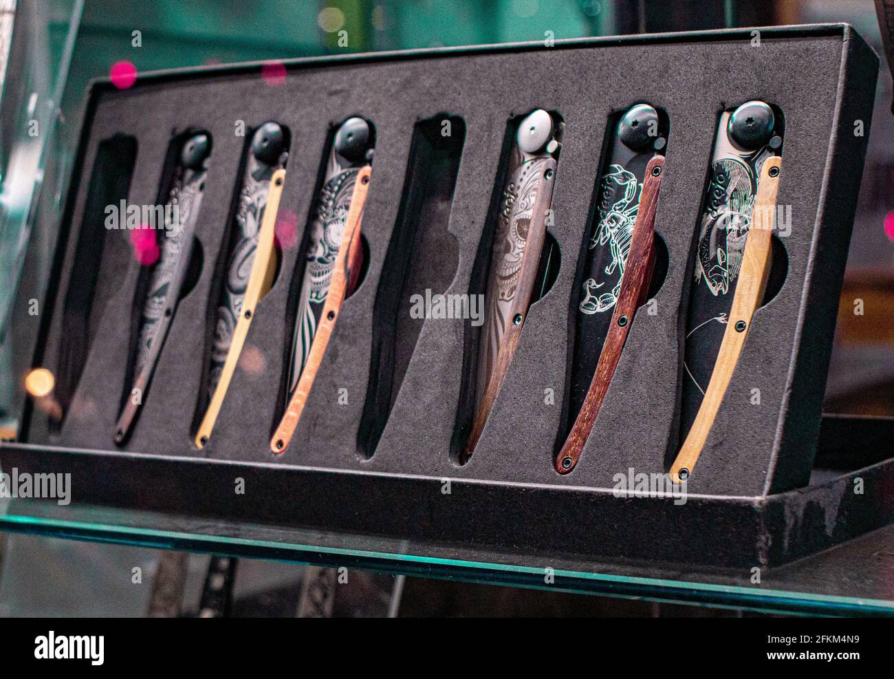 Un primo piano di una collezione di coltelli pieghevoli decorativi in una casella sul display Foto Stock