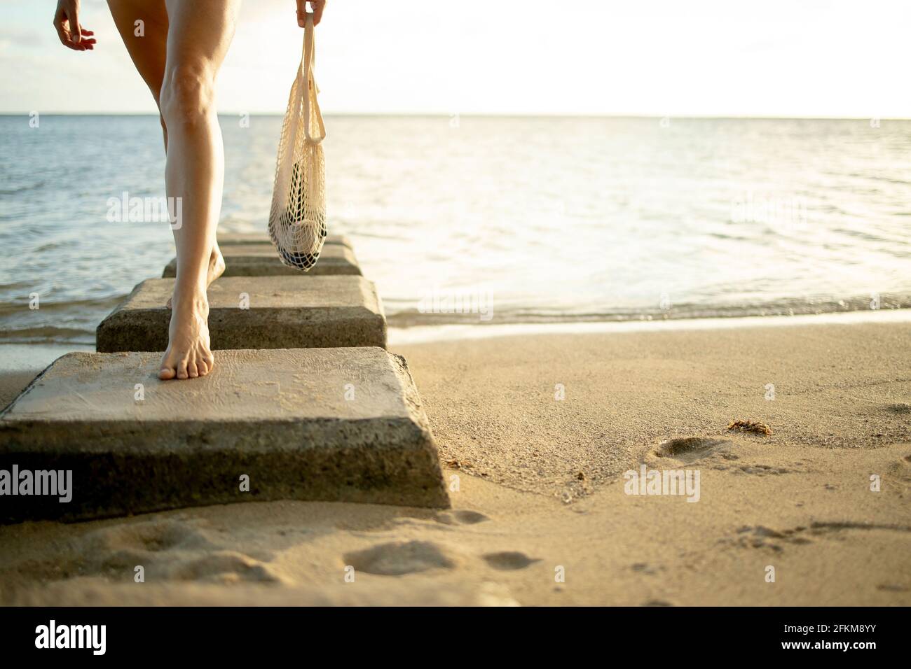 Donna che cammina sulla spiaggia di Honolulu con un riutilizzabile borsa Foto Stock