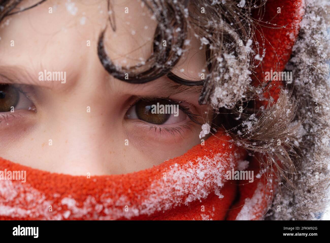 Un primo piano di un ragazzo vestito per Winter Coperto nella neve Foto Stock