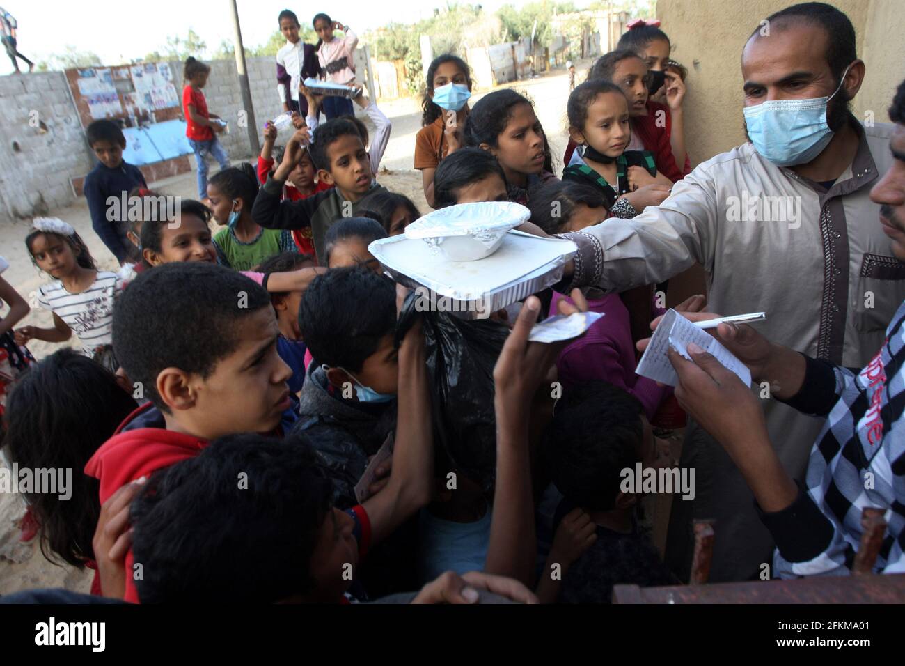 Deir al Balah, Gaza. 02 maggio 2021. I palestinesi ricevono una porzione di cibo, trasmesso alle famiglie povere, durante il mese santo islamico del Ramadan, a Deir al-Balah, nella striscia meridionale di Gaza, domenica 2 maggio 2021, i musulmani palestinesi distribuiscono i cibi ai bisognosi e ai poveri in occasione del santo mese di digiuno del Ramadan, Durante il quale i musulmani osservanti digiunano dall'alba al tramonto e dovrebbero trascorrere del tempo nella preghiera e nella contemplazione. Foto di Ismael Mohamad/UPI Credit: UPI/Alamy Live News Foto Stock