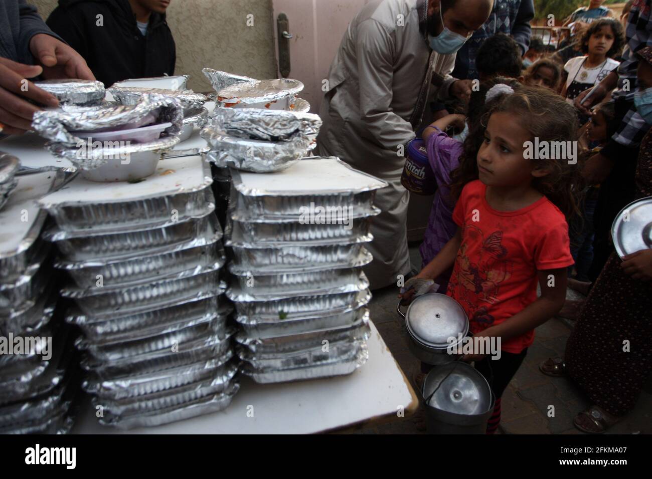 Deir al Balah, Gaza. 02 maggio 2021. I palestinesi ricevono una porzione di cibo, trasmesso alle famiglie povere, durante il mese santo islamico del Ramadan, a Deir al-Balah, nella striscia meridionale di Gaza, domenica 2 maggio 2021, i musulmani palestinesi distribuiscono i cibi ai bisognosi e ai poveri in occasione del santo mese di digiuno del Ramadan, Durante il quale i musulmani osservanti digiunano dall'alba al tramonto e dovrebbero trascorrere del tempo nella preghiera e nella contemplazione. Foto di Ismael Mohamad/UPI Credit: UPI/Alamy Live News Foto Stock