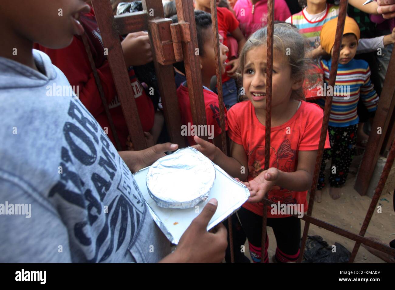 Deir al Balah, Gaza. 02 maggio 2021. I palestinesi ricevono una porzione di cibo, trasmesso alle famiglie povere, durante il mese santo islamico del Ramadan, a Deir al-Balah, nella striscia meridionale di Gaza, domenica 2 maggio 2021, i musulmani palestinesi distribuiscono i cibi ai bisognosi e ai poveri in occasione del santo mese di digiuno del Ramadan, Durante il quale i musulmani osservanti digiunano dall'alba al tramonto e dovrebbero trascorrere del tempo nella preghiera e nella contemplazione. Foto di Ismael Mohamad/UPI Credit: UPI/Alamy Live News Foto Stock