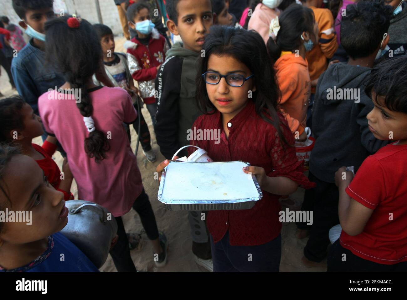Deir al Balah, Gaza. 02 maggio 2021. I palestinesi ricevono una porzione di cibo, trasmesso alle famiglie povere, durante il mese santo islamico del Ramadan, a Deir al-Balah, nella striscia meridionale di Gaza, domenica 2 maggio 2021, i musulmani palestinesi distribuiscono i cibi ai bisognosi e ai poveri in occasione del santo mese di digiuno del Ramadan, Durante il quale i musulmani osservanti digiunano dall'alba al tramonto e dovrebbero trascorrere del tempo nella preghiera e nella contemplazione. Foto di Ismael Mohamad/UPI Credit: UPI/Alamy Live News Foto Stock