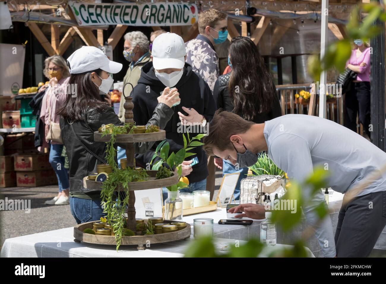 Seattle, Washington, Stati Uniti. 2 maggio 2021. Un fornitore di candele completa una transazione con i clienti al mercato agricolo di Ballard a Seattle. Questa settimana, il Washington state Health Department ha annunciato che più di una dozzina di contee rischiano di tornare alla fase 2 del piano di riapertura dello stato a causa dell'aumento dei casi e delle ospedalizzazioni COVID-19. Credit: Paul Christian Gordon/Alamy Live News Foto Stock