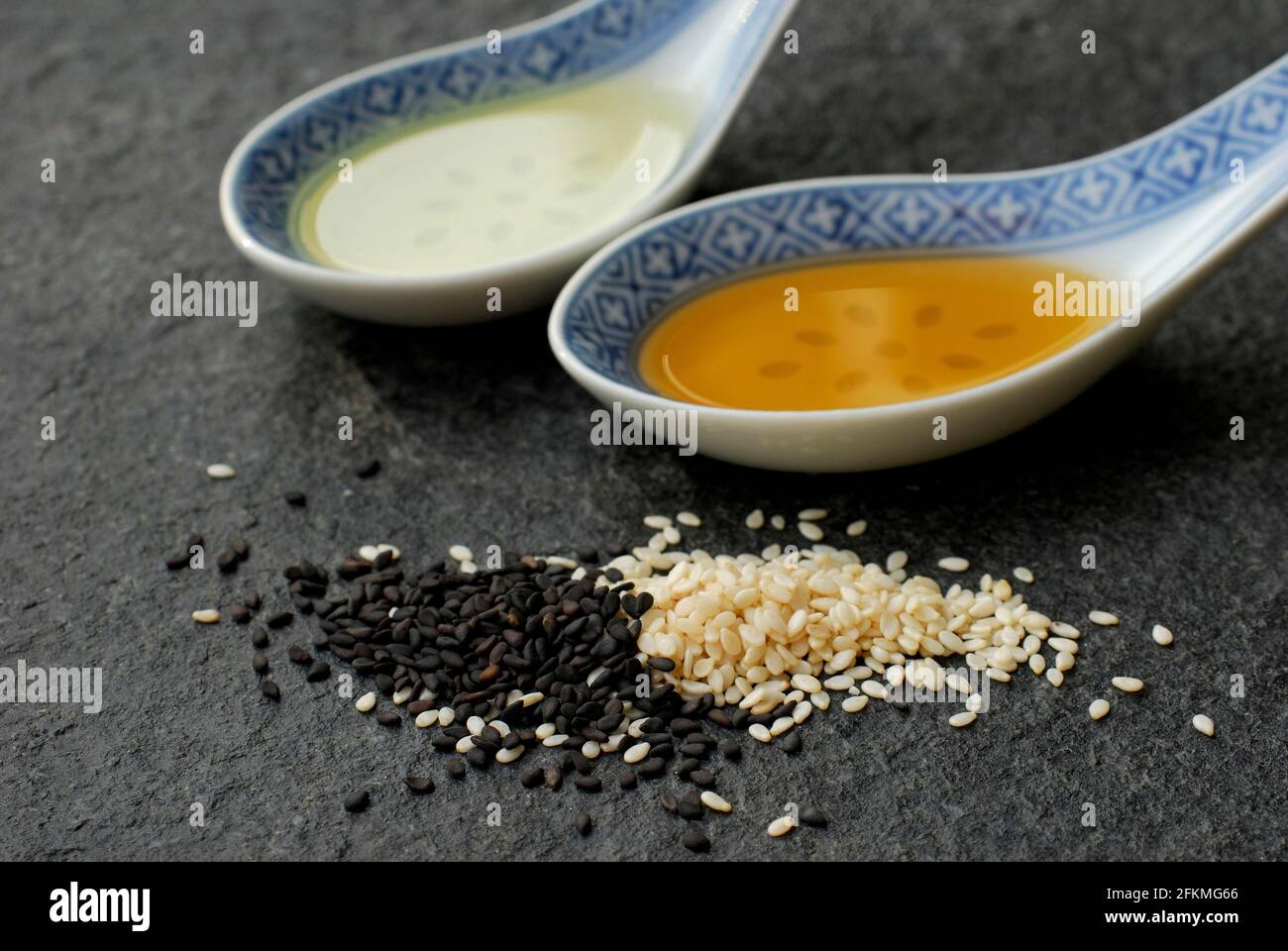 Sesamo bianco (Sesamum indicum) e nero, olio, cucchiaio Foto Stock