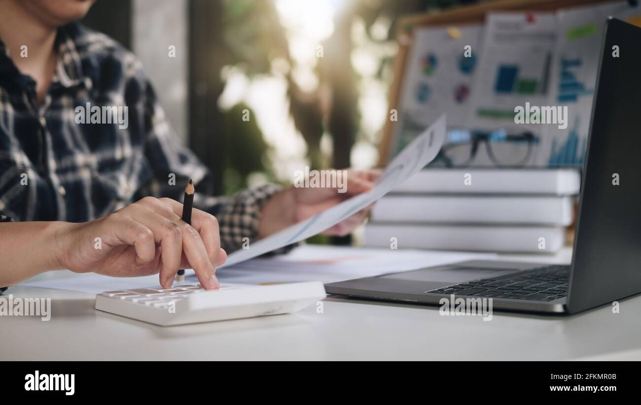 Primo piano di donna calcolare su calcolatrice gestire il budget di famiglia effettuare il pagamento sul computer. Femmina occupato prendersi cura delle spese di famiglia spese Foto Stock