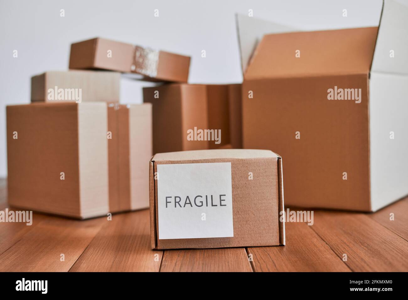 Piccola scatola di cartone con etichetta fragile su scrivania di legno Foto Stock