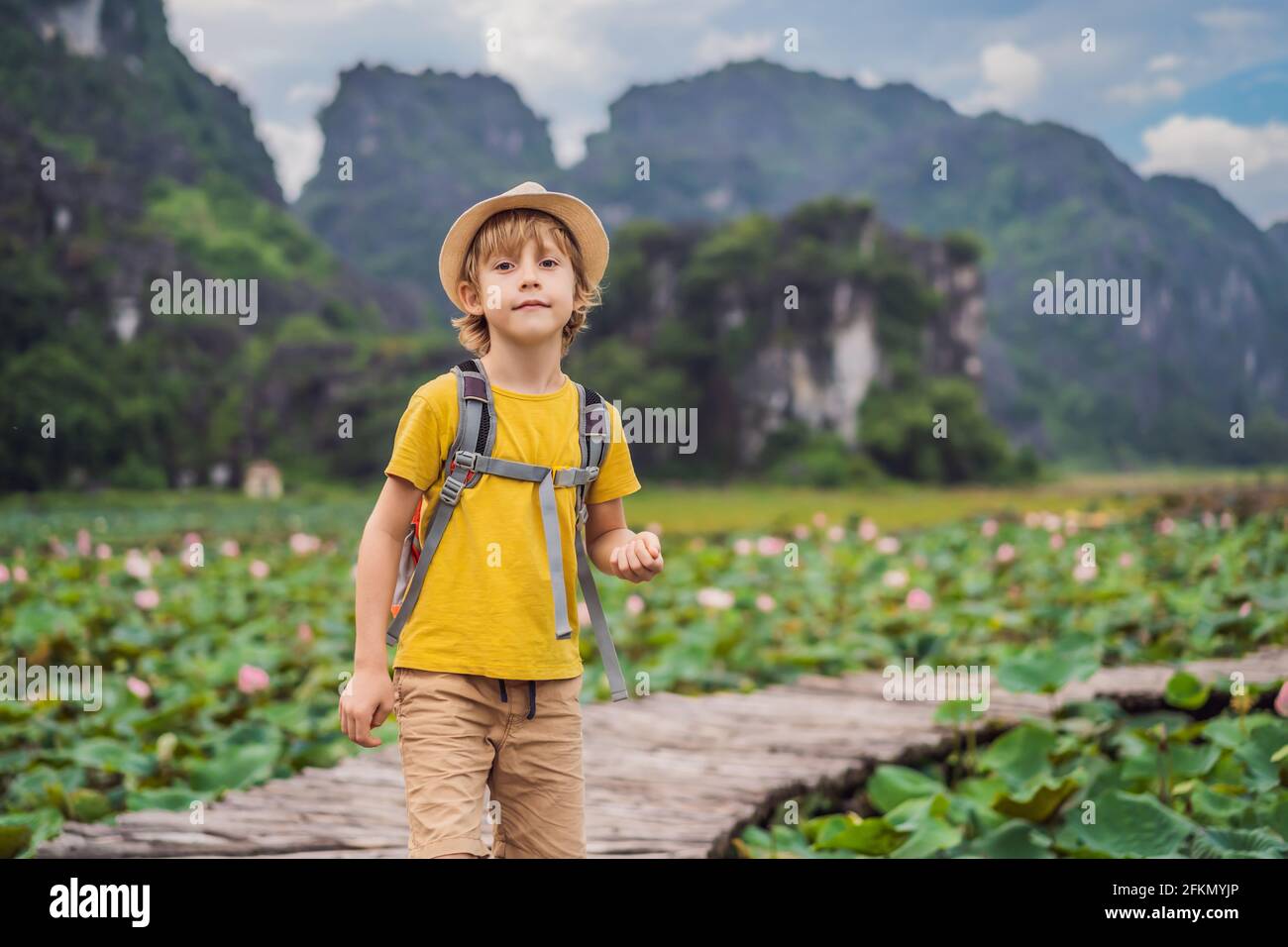 Ragazzo in un giallo sul sentiero tra il lago di loto. MUA Cave, Ninh Binh, Vietnam. Il Vietnam riapre dopo la quarantena Coronovirus COVID 19 Concept Foto Stock