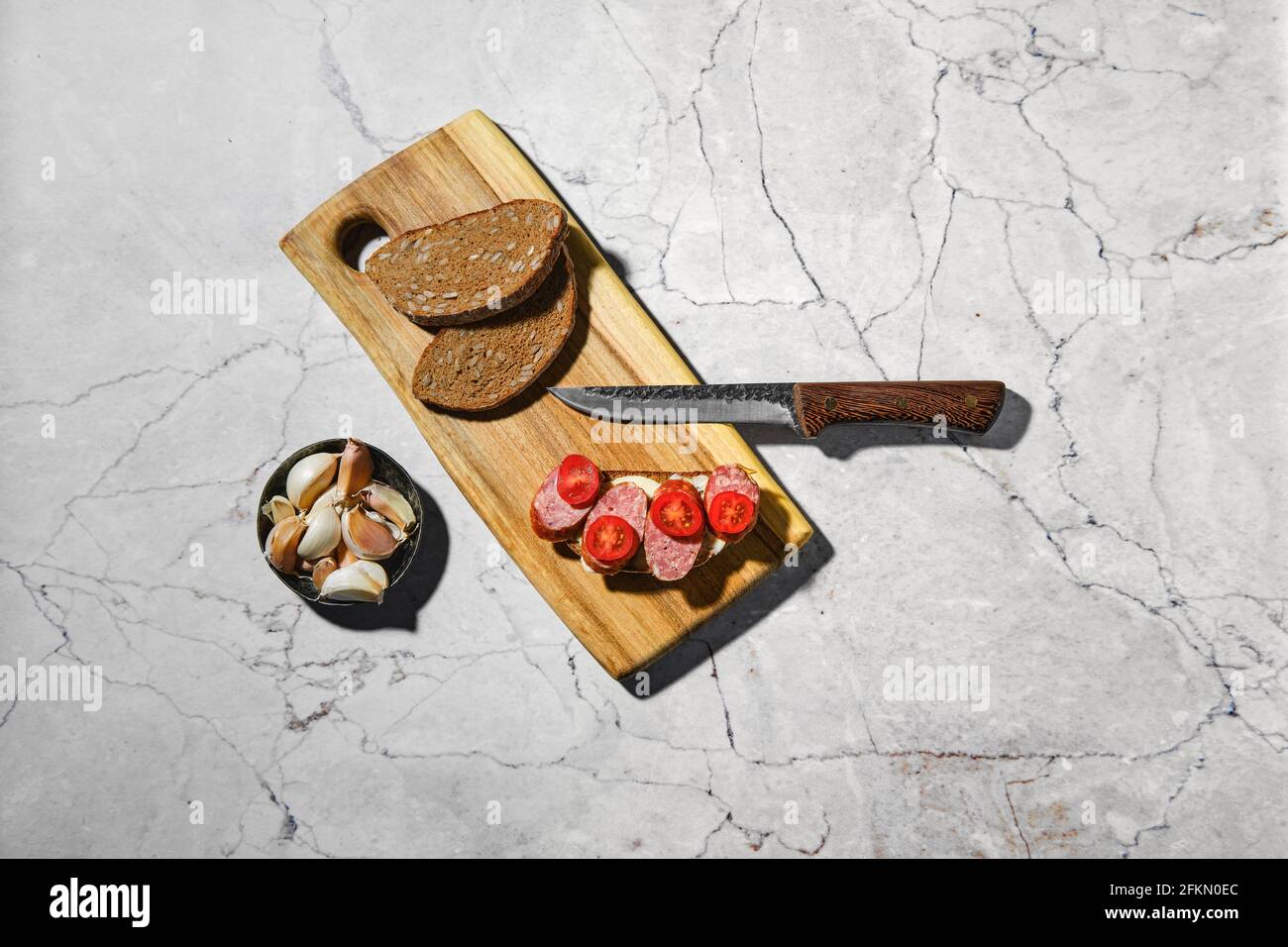 Vista panoramica del panino con anelli di salsiccia di maiale affumicata tagliere in legno sul tavolo da cucina Foto Stock