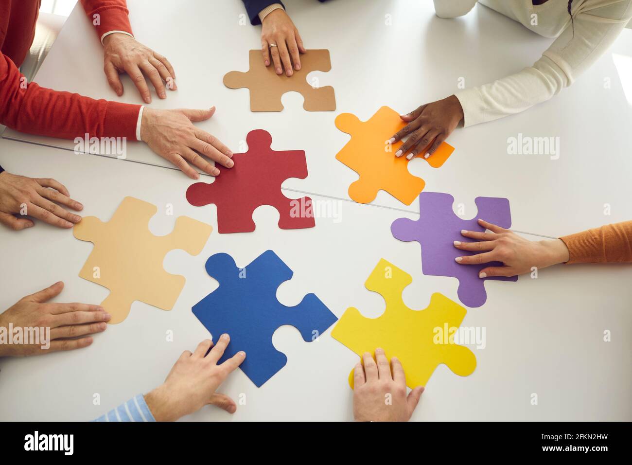 Team di uomini d'affari che si uniscono pezzi di puzzle colorati come un metafora per il lavoro di squadra Foto Stock