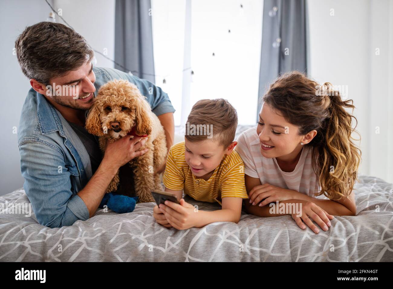 Felice famiglia con i dispositivi moderni e cane divertirsi, giocando a casa Foto Stock