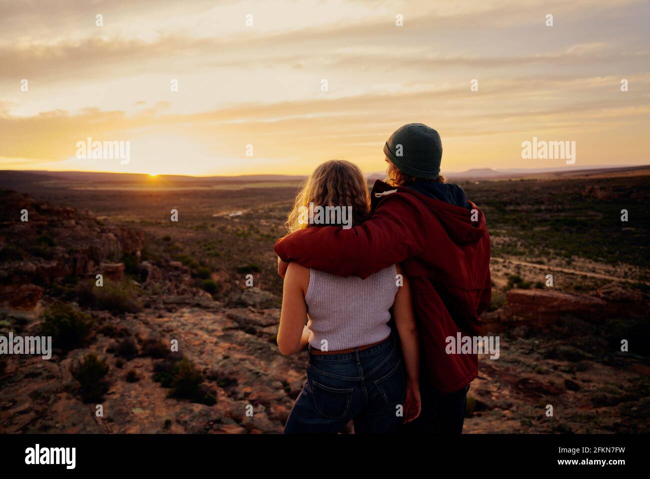 Vista posteriore di una giovane coppia godendosi insieme guardando la splendida alba in piedi sulla montagna Foto Stock