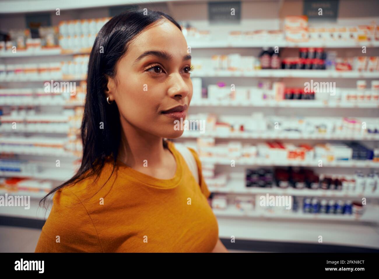 Giovane African American Woman in piedi in farmacia guardando lo scaffale Foto Stock