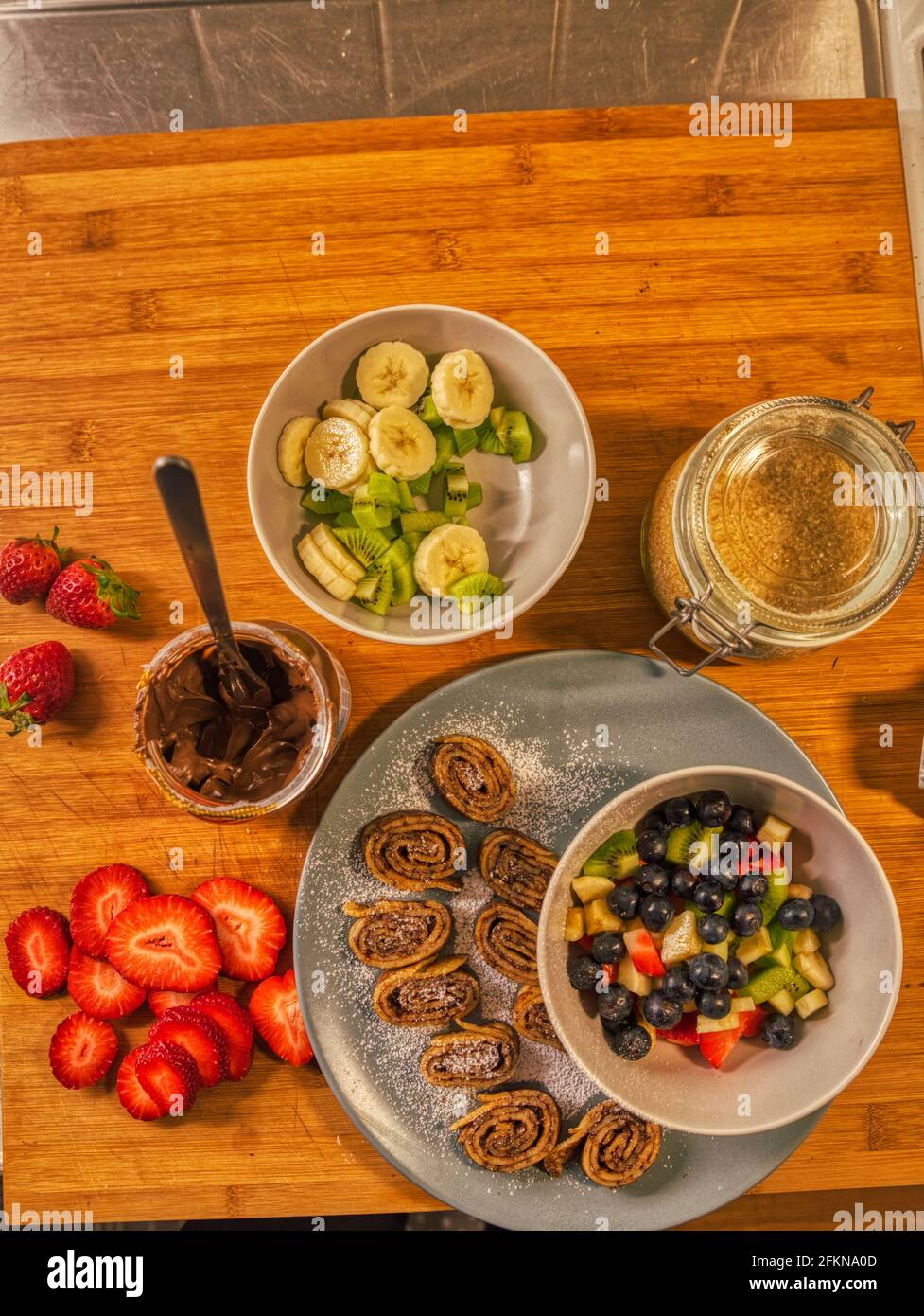 Vista dall'alto o dall'alto della crema di nocciole al cioccolato (crema di Nutella) panini crespati con frutta fresca multicolore e una spruzzata di zucchero a velo dolce Foto Stock