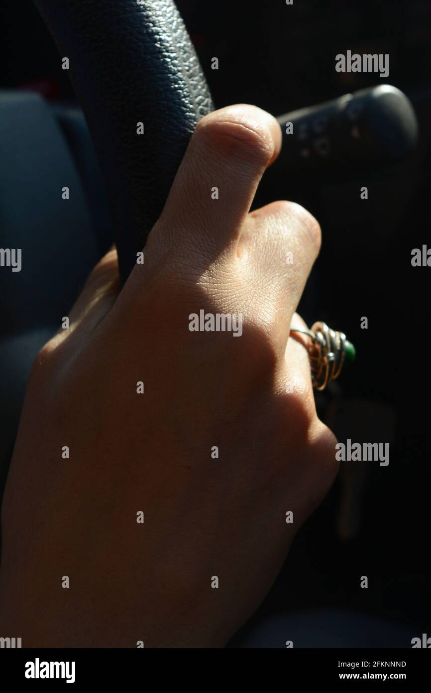 mano femminile che prende un volante di una macchina che guida sulla strada al tramonto con un anello su di lei dito Foto Stock mano femminile che prende un volante di una macchina che guida sulla strada al tramonto con un anello su di lei dito Foto Stock