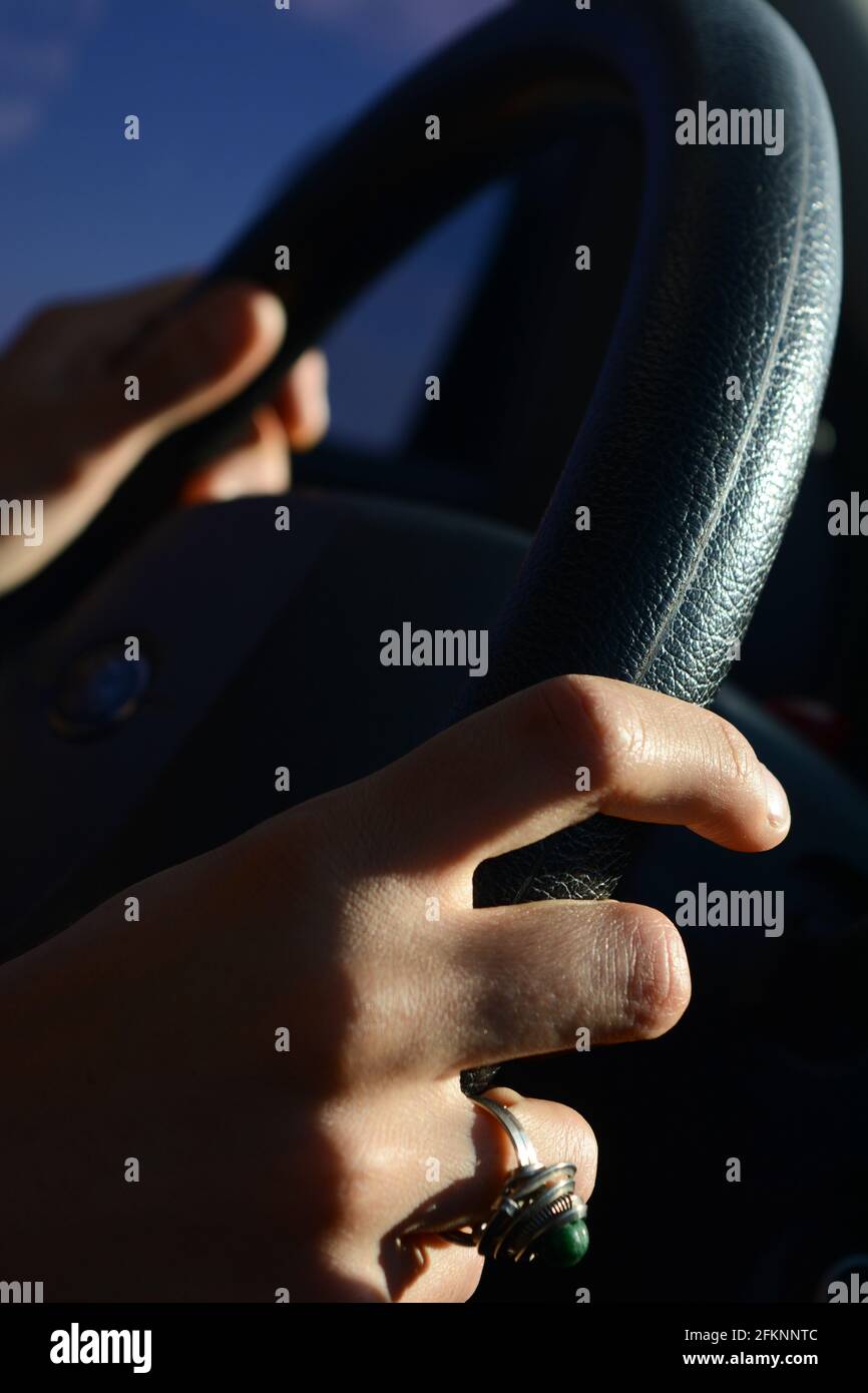 mano femminile che prende un volante di una macchina che guida sulla strada all'alba con un anello sul il dito e il finestrino della vettura sullo sfondo Foto Stock mano femminile che prende un volante di una macchina che guida sulla strada all'alba con un anello sul il dito e il finestrino della vettura sullo sfondo Foto Stock