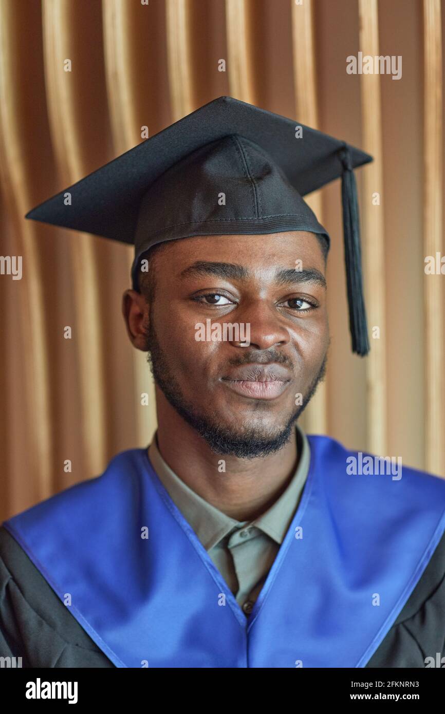 Primo piano verticale ritratto di un giovane afro-americano che indossa una  laurea abito e cappello sorridenti alla macchina fotografica mentre si posa  in casa Foto stock - Alamy