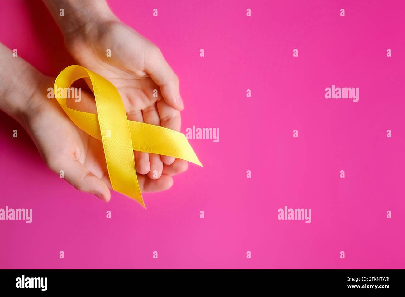 Mano della donna che tiene il nastro giallo - vescica, fegato e simbolo di consapevolezza del cancro osseo. Concetto di prevenzione del cancro dei bambini. Sfondo isolato, copia sp Foto Stock