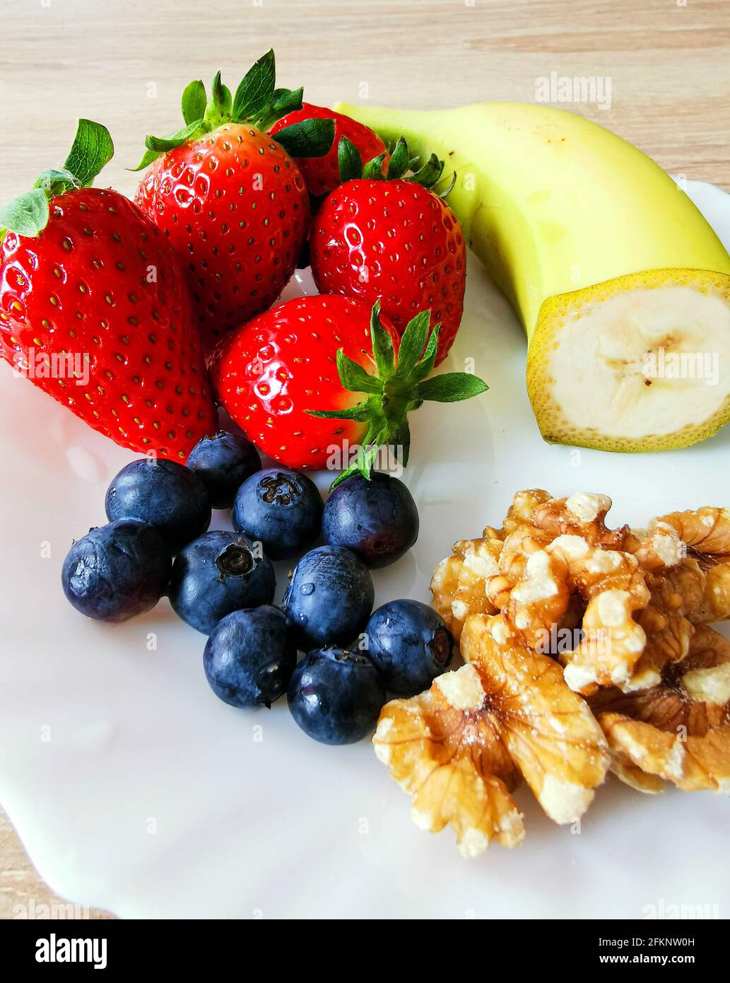 Uno spuntino sano. Noci, mirtillo di highbush, fragole e banana Foto Stock