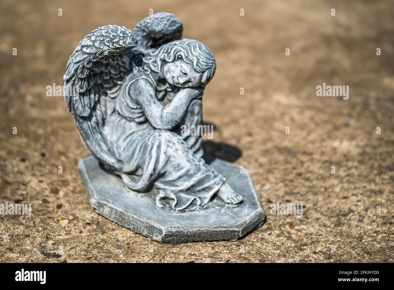 Fuoco vicino e selettivo di una statuetta dell'angelo in a. cortile posteriore privato con profondità di campo intenzionale poco profonda e. bokeh Foto Stock