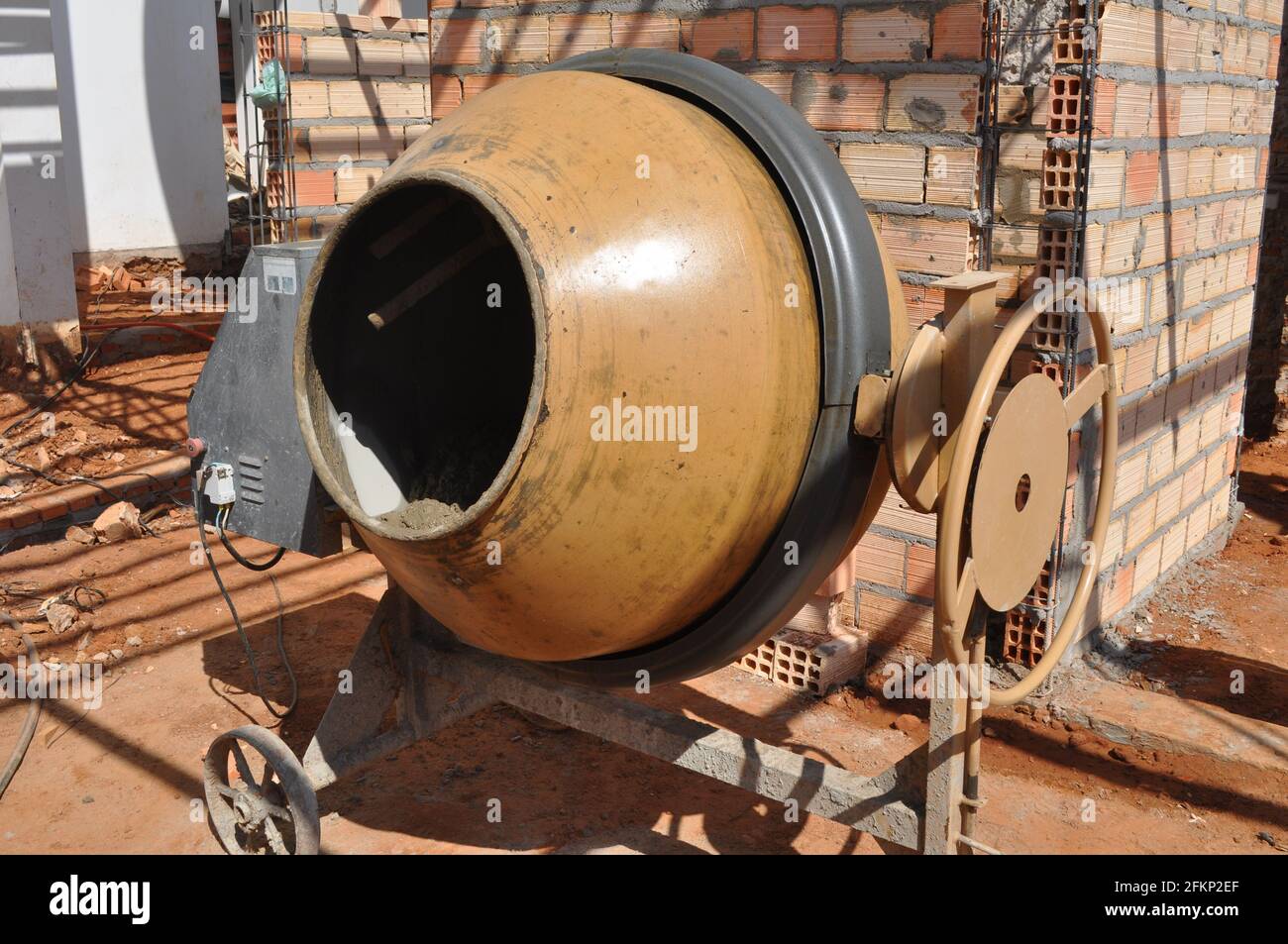 Cantiere. Macchina per la miscelazione del cemento in un cantiere in Brasile, Sud America, sulla parete posteriore di blocchi e blocchi liberi sul terreno Foto Stock