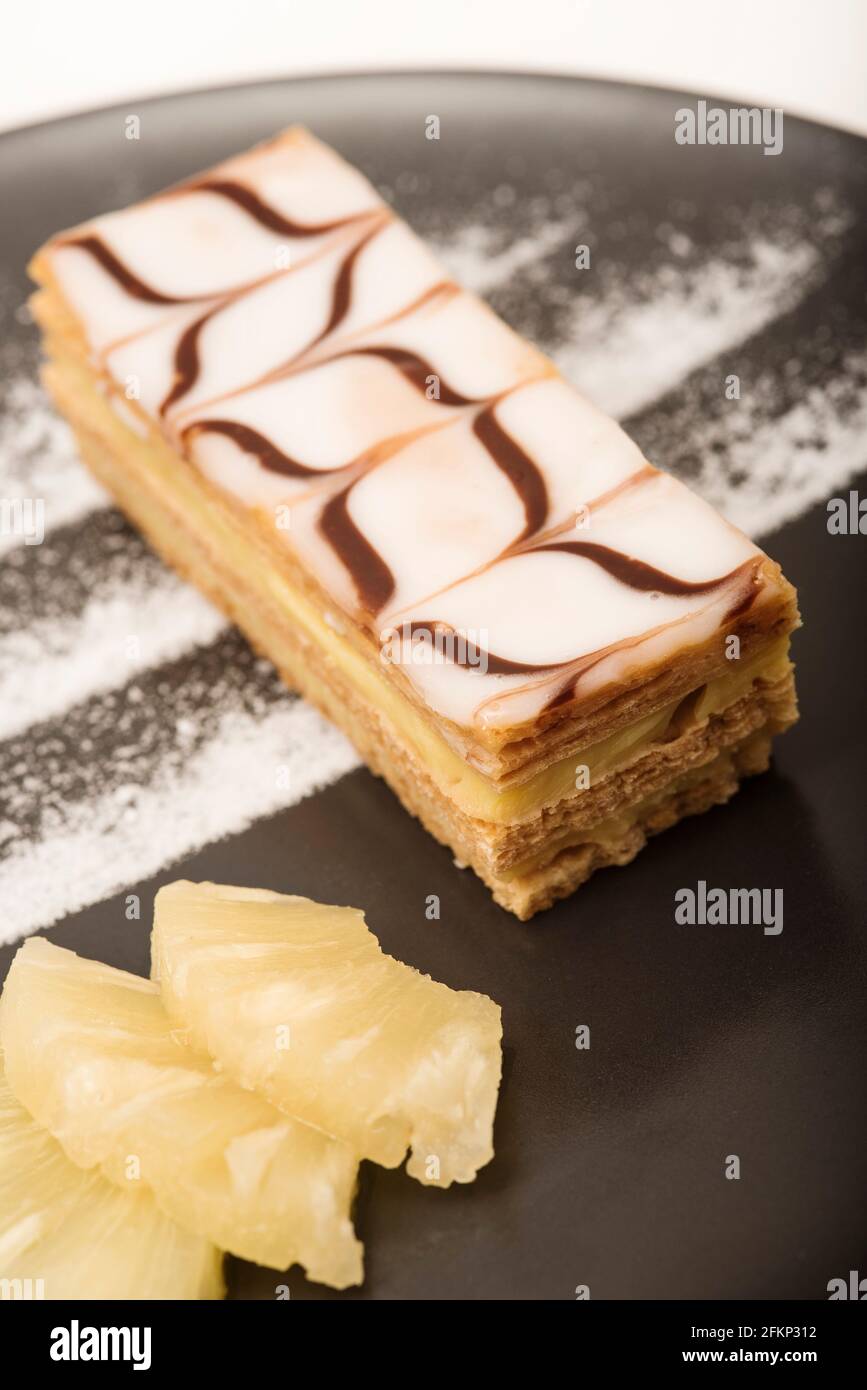 Presentazione in stile Nouvelle Cuisine di una pasticceria Millefeuille, nota anche come fetta di vaniglia o fetta di crema servita con ananas. Foto Stock
