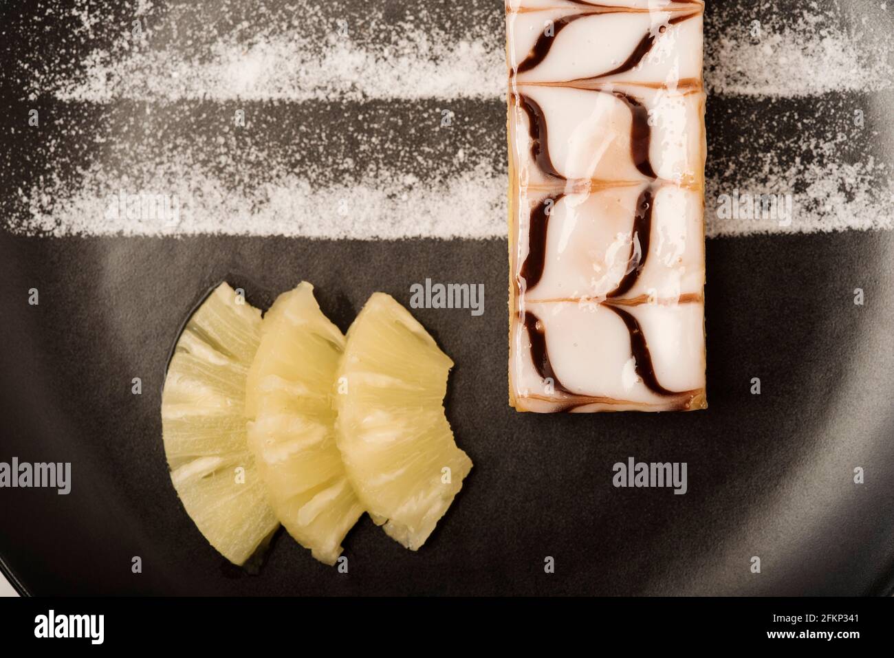 Presentazione in stile Nouvelle Cuisine di una pasticceria Millefeuille, nota anche come fetta di vaniglia o fetta di crema servita con ananas. Foto Stock