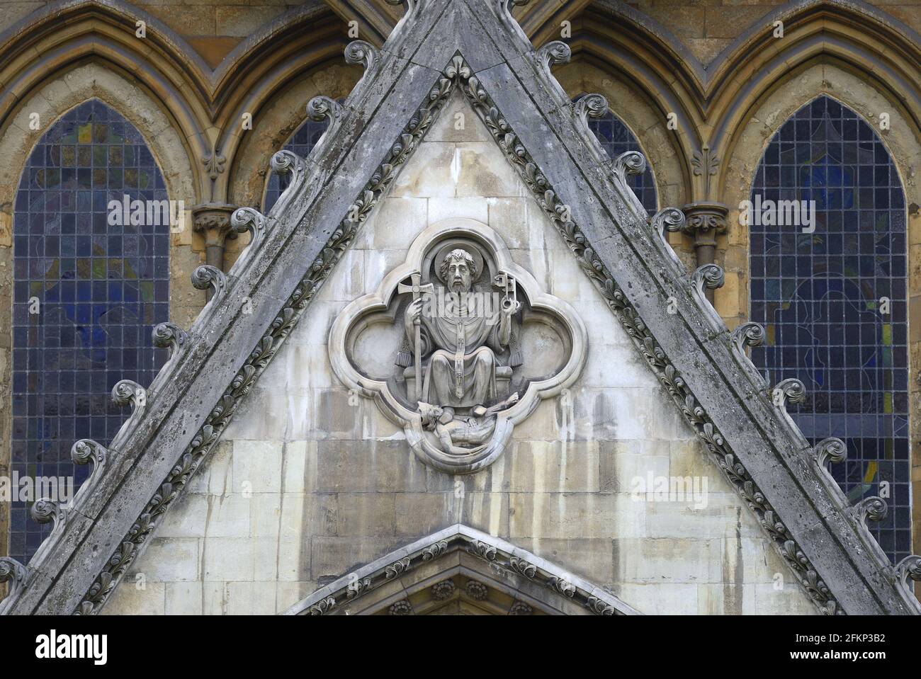 Londra, Inghilterra, Regno Unito. Scultura in pietra di San Pietro calpestata sul Diavolo, sopra la porta nord Foto Stock