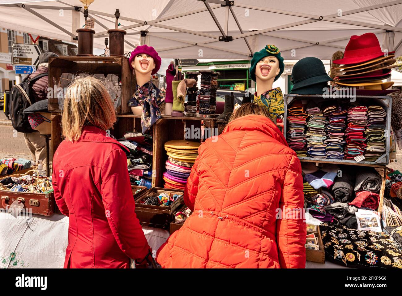 Teste ridenti. Due Signore peruse i cappelli in vendita al Alresford Brocante, un mercato locale delle pulci, Alresford, Hampshire, Regno Unito Foto Stock