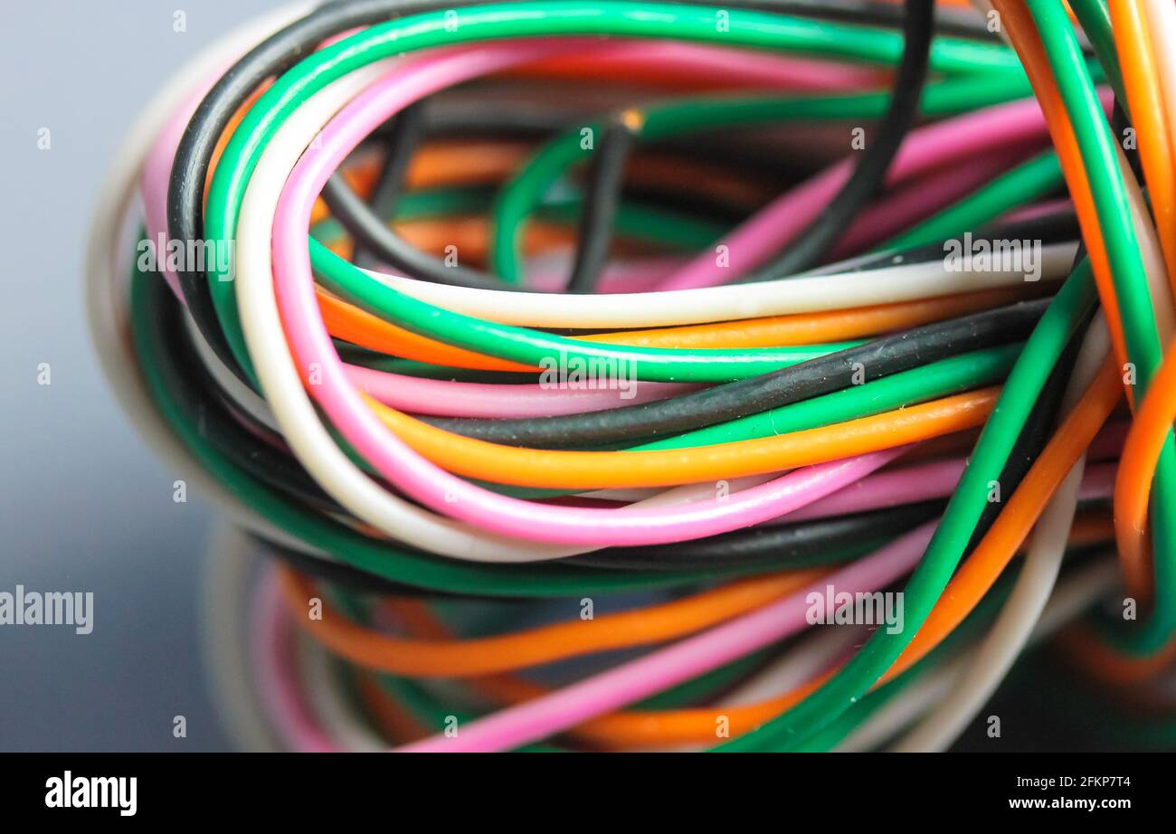 Un fascio di cavi multicolore elettrici, per auto, computer, telefonici  intrecciati insieme sullo sfondo. Cavi arancioni, verdi, rosa, bianchi su  sfondo grigio Foto stock - Alamy