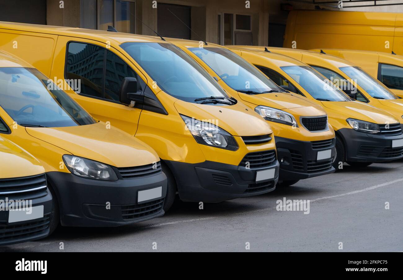 Furgoni di consegna gialli parcheggiati di fila Foto Stock