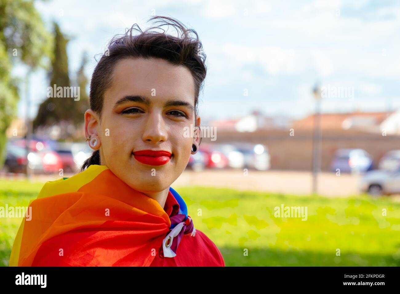 Una ragazza transgender con la bandiera gay sulle spalle. Persone autentiche non binarie. Foto Stock
