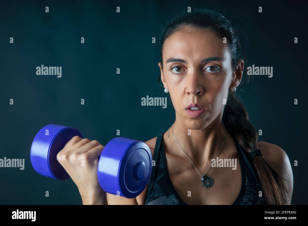 ritratto di donna che solleva pesi in esercizio fisico isolato su sfondo scuro. Foto Stock