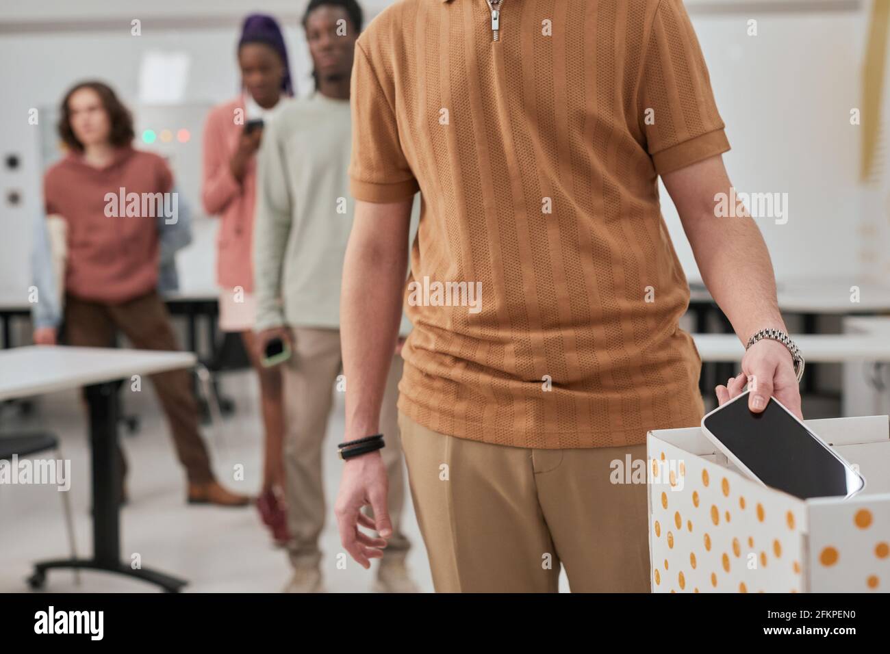 Un'immagine ritagliata di un adolescente irriconoscibile che mette lo smartphone in scatola in una classe senza gadget a scuola, spazio di copia Foto Stock