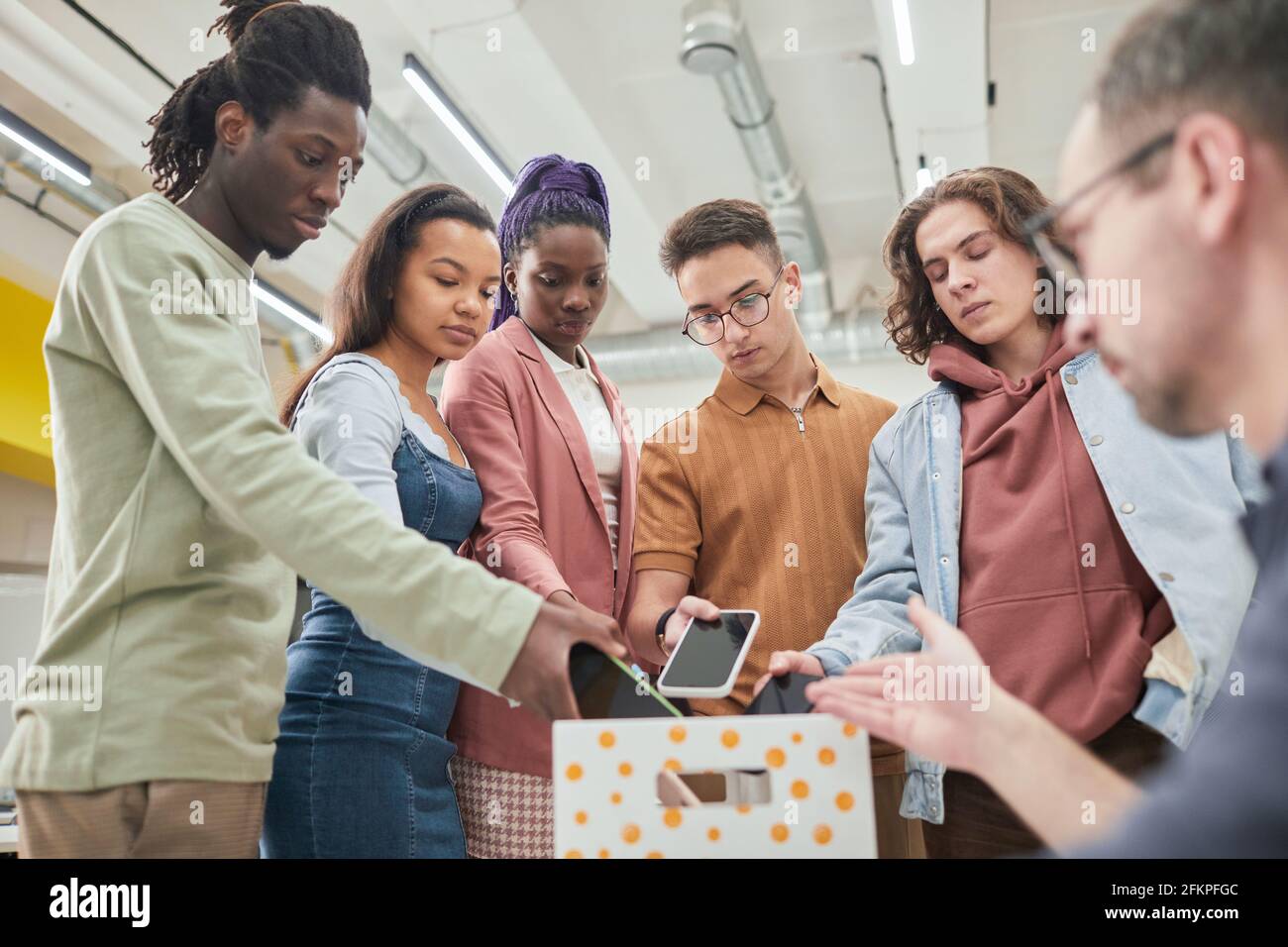 Gruppo eterogeneo di adolescenti che mette gli smartphone in scatola in classe no gadget a scuola, spazio di copia Foto Stock
